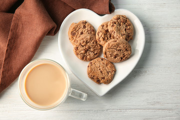 Plate with delicious oatmeal cookies and cup of coffee on table
