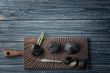 Black garlic (Allium sativum) on wooden board