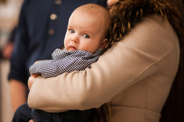 Baby on mothers hands in church baptism ceremony