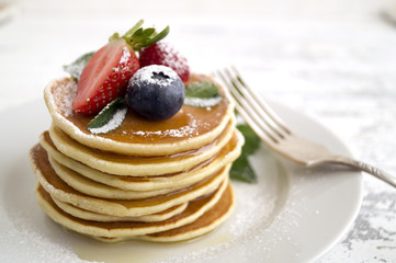 American pancakes with berries on a light background.