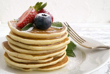 American pancakes with berries on a light background.