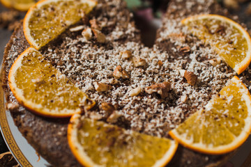 Beautiful and tasty chocolate cake with orange and nut on a dark background