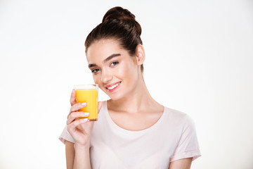 Close up picture of glad gorgeous woman drinking sweet orange juice from transparent glass with smile over white background