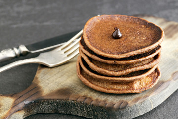 Fototapeta na wymiar Chocolate pancakes with chocolate sauce on a dark background.