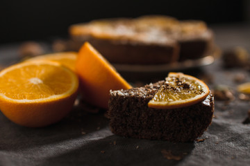 Beautiful and tasty chocolate cake with orange and nut on a dark background