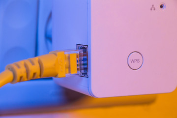 WiFi extender in electrical socket on the wall with ethernet cable plugged in