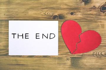 Broken heart and white paper with text the end on wooden table,relationship breakup concept.