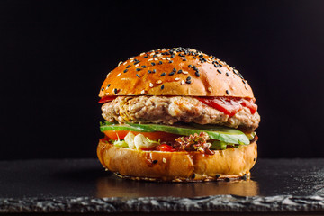 Hamburger on a black slate board. Bun with sesame seeds.