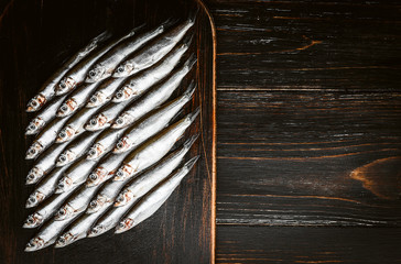 fresh raw fish anchovy and sprat on a wooden surface
