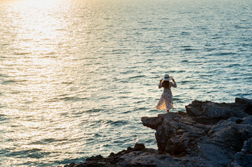 Young woman standing on the top of rock and looking at the seashore and sunset in Si chang island.