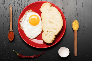 Food placed on red plate on black background, top view.