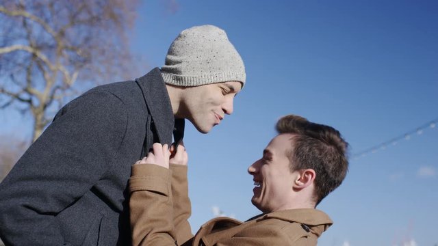 Happy young diverse same sex couple hugging and sharing a kiss