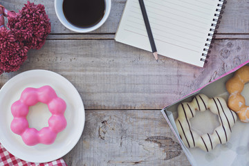 Top view,Opened notepad and cup of coffee with donut on wood background.