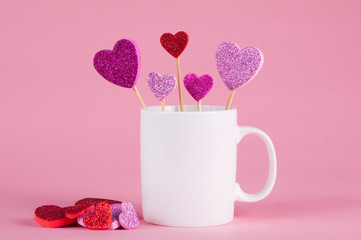 White mug on a pink background with hears for Valentine's day