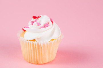 cupcake with heart confetti on a pink background for valentine's day