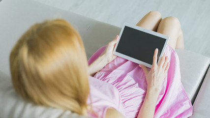 Woman at home relaxing reading on the tablet 