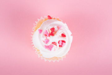 cupcake with heart confetti on a pink background for valentine's day