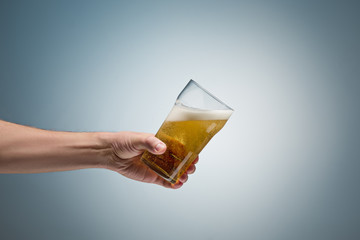Closeup of a male hand holding up a glass of beer