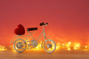 Naklejka premium Valentine's day romantic background with white vintage bicycle toy and heart on it over wooden table.