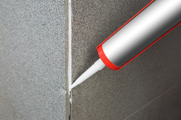 Sealant gun crackcovers the crack in the floor of the wall tile concrete