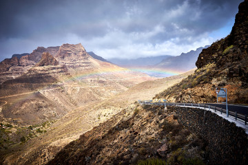 Rainbow over road into mountain landscape of Gran Canaria island, Spain / Valley of 