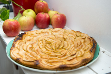 apple pie with red and yellow apples in the background
