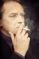 Older caucasian man trying electronic cigarette on black background