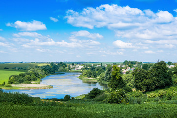 Fototapeta na wymiar summer landscape, seen river, trees and clear blue sky with clouds