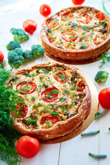 cheese cake with broccoli, green beans, tomatoes and Dill on white wooden table