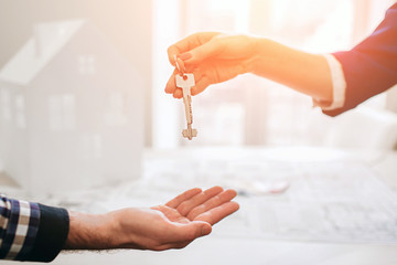 Young family couple purchase rent property real estate . Agent giving consultation to man and woman. Signing contract for buying house or flat Giving keys to couple of customers. Close up