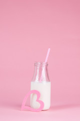 bottle of milk on a pink background with a pink straw