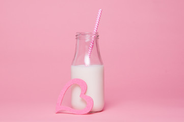 bottle of milk on a pink background with a pink straw