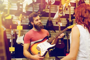 Photo sur Plexiglas Magasin de musique assistant montrant la guitare du client au magasin de musique