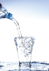 Pouring water and splashing in the glass with reflection on mirror.