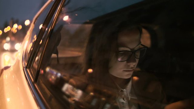 Tired Young Woman Reaching for her Tablet in the Car