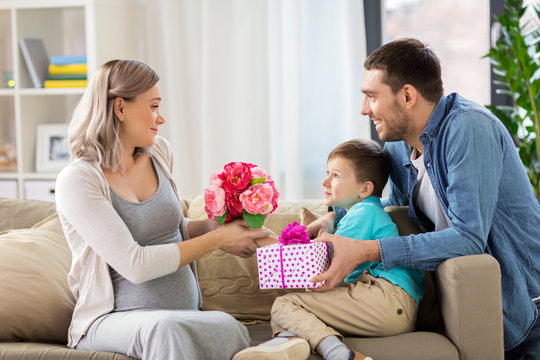 family giving present to pregnant mother at home
