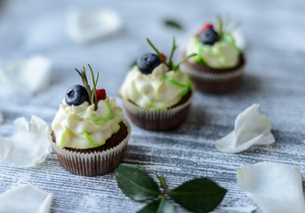 Tasty cupcakes and roses on wooden table