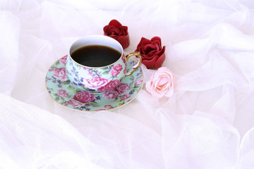 Fototapeta na wymiar Morning hot coffe in mug and little red and pink flowers on white satin background. Closeup, top view. Seasonal, morning coffee, Sunday relax and still life concept. Free place for text
