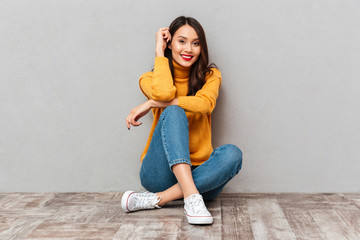 Smiling brunette woman in sweater sitting on the floor