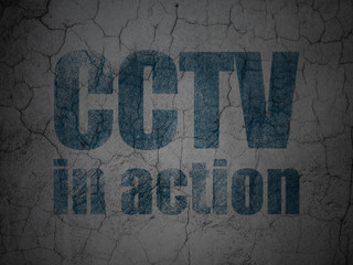 Security concept: Blue CCTV In action on grunge textured concrete wall background