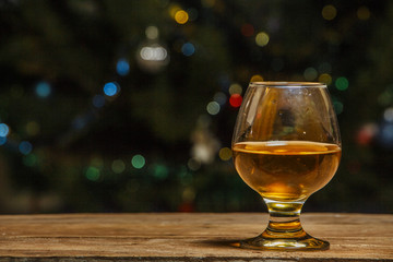 A glass of cognac or whiskey on a village table in the background of lights.