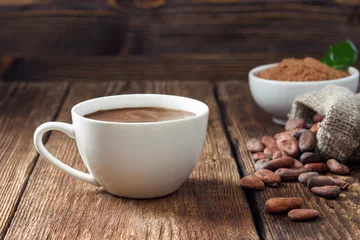 Foto op Plexiglas Cacaodrank in witte mok, cacaopoeder en cacaobonen op houten tafel. © Dmitrii