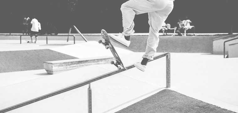 Skater performing jump trick in skate park - Young man training with skateboards in urban contest - Extreme sport and youth lifestyle - Soft focus on feet - Black and white editing