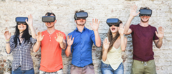 Young students wearing virtual reality glasses outdoor - Happy people having fun with new...