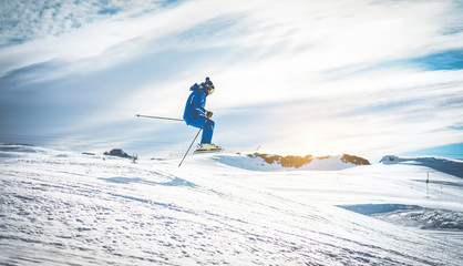 Ski athlete performing acrobatic jump on downhill at sunset