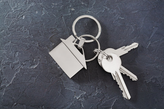estate concept with key, keychain with house symbol, stone background