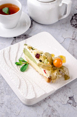 Top view of glass cup of tea with mint, white kettle, cake green tea portion on white plate on table, gray background. Restaurant kitchen concept