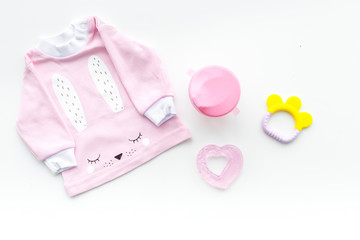 Cute pink baby clothes for girl. Shirt,, toy, bottle on white background top view