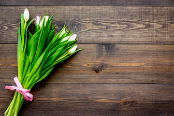 First spring flowers. Bouquet of pale pink tulips on dark wooden background top view copy space