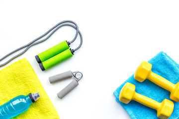 Fitness concept. Dumbbells, towel, sport drink, jump rope on white background top view copy space